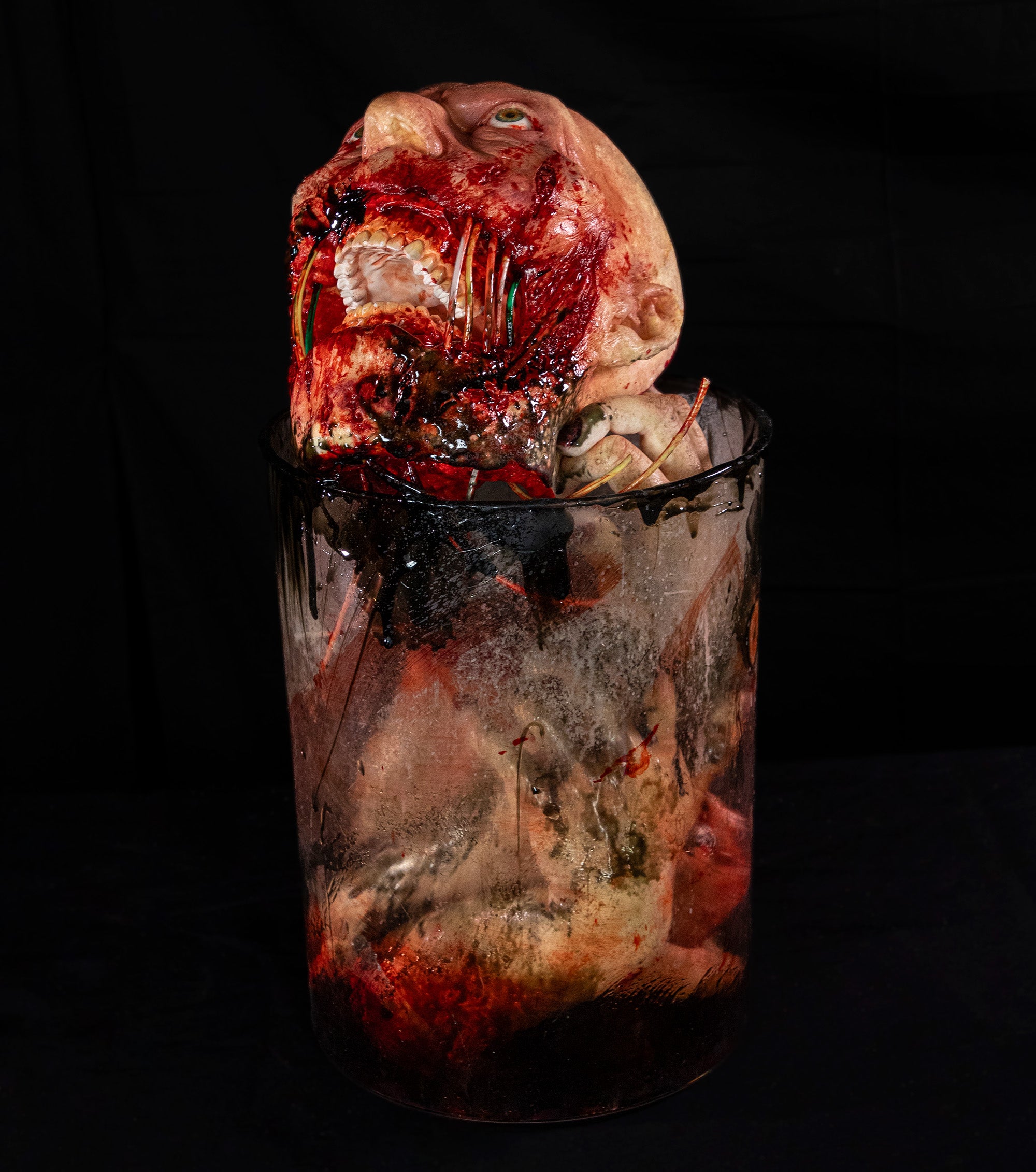 Gory scene with a severed head in a jar on a black background